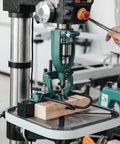 Mortising attachment for drill press; green steel frame, chisel, and wood block clamped.