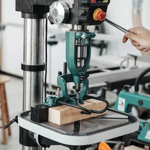 Mortising attachment for drill press; green steel frame, chisel, and wood block clamped.