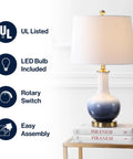 Gradient 25 Inch Ceramic And Brass LED Table Lamp For Bedroom Living Room Office And College Desk Nightstand Accent Light With Included LED Bulb For A Chill Vibe Contemporary Traditional Style In White Navy Finish on table with white shade