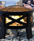 Heavy Duty Portable 26 Inch Steel Fire Pit With Grill Grate And Spark Screen on rocky beach