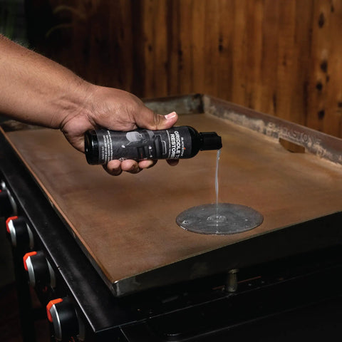 Griddle Top Restoration Kit Includes 8 Oz Griddle Top Restorer And Two Heavy Duty Scrub Pads For Quick Griddle Cleanup And Easy Maintenance On Griddle Plates Side Shelves Cookware And Tools. Hand applying restorer to a griddle plate.