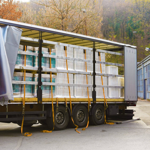 Open trailer loaded with palletized goods secured using Green 12 Ft Endless Round Sling With 5300 Lb Vertical Capacity And 10600 Lb Basket Capacity Built Tough Heavy Duty Lifting Sling 4200 Lb Choker Capacity Quality USA Made.