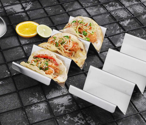 Stainless Steel Taco Holders 4 Pack, Durable Taco Stand Rack Tray Style with filled tacos, lemon, and lime slices shown on a tile surface.