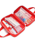 Open red compact first aid kit bag with visible compartments and medical supplies, featuring dual handles for grab and go use.