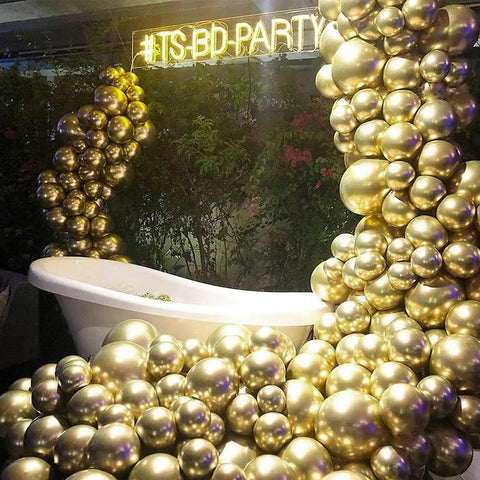 Top Tier 12 Inch Gold Latex Helium Balloons 50 Pack Slay Party Decorations displayed in a decorative arrangement near a bathtub.