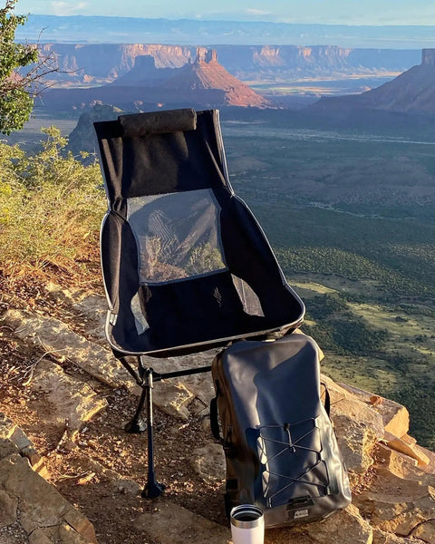 Chillin Chair Ultra Lightweight Foldable Portable Outdoor Seat in scenic landscape setting with carry bag and mug.