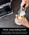 Person using R-ES601 Luxe Café Premier Series 3-In-1 Espresso Machine for frothing milk into cappuccino beside the machine.