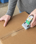 Person sealing a cardboard box with EZ Start Packing Tape With One Handed Dispenser 1.88 Inch By 55.5 Yard Crystal Clear Tape Roll