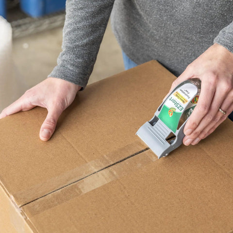 Person sealing a cardboard box with EZ Start Packing Tape With One Handed Dispenser 1.88 Inch By 55.5 Yard Crystal Clear Tape Roll
