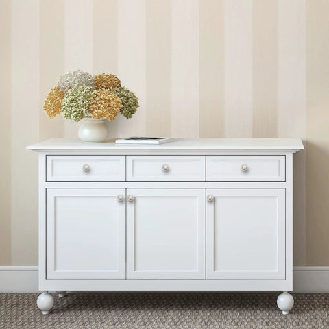 White cabinet with brushed nickel round knobs, smooth gliding drawers, topped with a decorative flower vase.