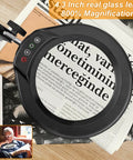 Big 8X Magnifying Glass With Light And Stand Clamp On LED Desk Lamp Arm over newspaper showing magnified text.