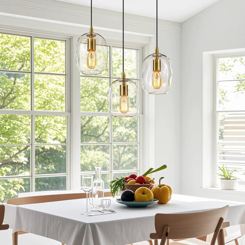 Pendant Lights Kitchen Island, Hand-Blown Clear Glass Brass Gold 9 Inch H hanging above a modern dining table with fresh fruits.