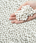 Hand holding 8 Pound Ceramic Tumbling Media Balls For Rock Tumblers Reusable White Alumina Pellets Three Tenths Inch Diameter