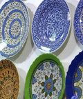 Colorful decorative plates displayed on a wall using decorative plate hangers for five and a half inch to eight inch display.