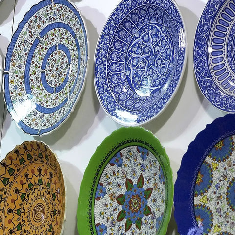 Colorful decorative plates displayed on a wall using decorative plate hangers for five and a half inch to eight inch display.