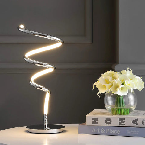 Gold 19.75 Inch Modern Scribble Dimmable Integrated LED Table Lamp With 3 Way Touch Sensor next to books and flowers on table