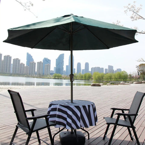 Outdoor Round Tablecloth 60 Inch With Zipper Umbrella Hole Water Resistant Polyester Durable Patio Garden Table Cover in black, installed on a table under a green umbrella with chairs, cityscape background.