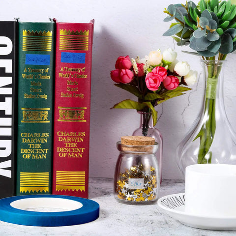 Blue 1/2 Inch Painter Drafting Tape For Crafting And Masking, 55 Yards Long, near books and decorative flowers.