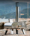 12 Inch Dual Fuel Outdoor Pizza Oven Portable Pellet And Gas Fueled Wood Fired Pizza Maker With Stone No Tools Needed Easy Switch Between Pellets And Gas Built In Gas Burner For Backyard Pizza Nights on rocky terrain.