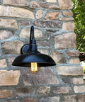 One Light Outdoor Wall Lamp With Metal Shade In Imperial Black Dimmable 120V 60W E26 Base Durable Weather Resistant Outdoor Lighting Fixture For Porch Patio Or Entry Classic Industrial Style Dope Look mounted on stone wall.