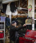 Person using Spill Ender 3 In 1 Paper Towel Holder For Cars And Campsites in garage setting, near a green vehicle.