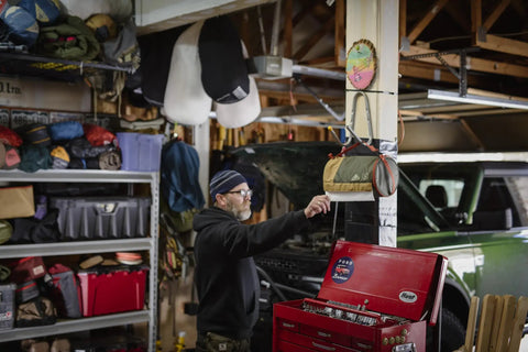 Person using Spill Ender 3 In 1 Paper Towel Holder For Cars And Campsites in garage setting, near a green vehicle.