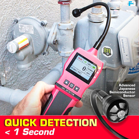 Front view of pink handheld gas detector with LCD screen held beside a gas meter and piping.