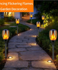 Six Pack Solar Torch Lights With Realistic Flickering Flame lighting a garden pathway at night, enhancing outdoor ambience.