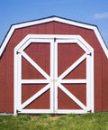 Red barn with white trim doors on a grassy field