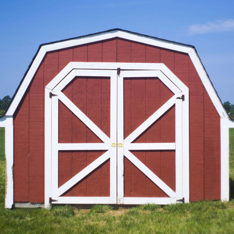 Red barn with white trim doors on a grassy field