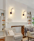 MATAMEYE Battery Operated Wall Sconce Set of 2, Dark Chocolate Wall Light mounted on a wall beside cozy armchairs in a living room.