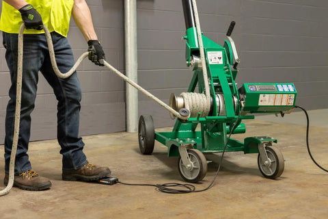 Greenlee 10k Tugger Package Featuring Dual Speed Motor For Faster Pulls, showing a user operating the mobile cable tugger.
