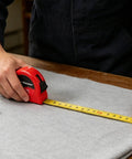 Person using a tape measure on fabric from the All-In-One 140-Piece Home Tool Set For DIY And Home Repairs With Organized Storage Case