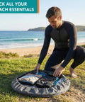 Man using Wetsuit Changing Mat And Dry Bag For Surfing And Kayaking All In One 30 Inch Leakproof Gear Mat on beach