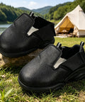 Heavy Duty Steel Toe Shoe Covers With Adjustable Strap Safety Overshoes For Work on rocks, black breathable fabric, outdoor setting.
