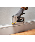 User fastening baseboard using Heavy Duty Staple And Brad Gun For Fast, Precise Fastening In Woodworking And Upholstery Projects, Durable Multi Color Tool