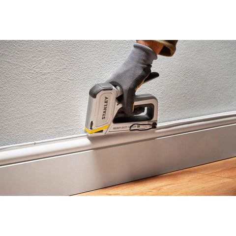 User fastening baseboard using Heavy Duty Staple And Brad Gun For Fast, Precise Fastening In Woodworking And Upholstery Projects, Durable Multi Color Tool