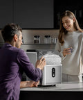 Top Tier Nugget Ice Maker Producing Thirty Three Pounds Daily Of Crisp Chewable Crushed Ice With Easy Self Cleaning Setup and Clear Viewing Window being used by a couple in a modern kitchen.