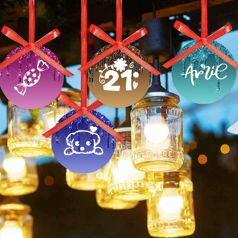 Colorful hanging ornaments with red ribbons, candy, bear, and text designs, glowing lights in background.