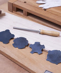 Nine Piece Cabinet Scraper Set For Woodworking With Burnisher and four black metal scrapers on a wooden workbench