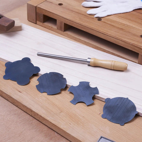 Nine Piece Cabinet Scraper Set For Woodworking With Burnisher and four black metal scrapers on a wooden workbench
