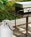 Propane Hose Regulator With Gauge 3Ft Replacement Hose for Outdoor Grills connected to a propane tank and grill setup.
