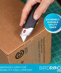 BirdRock Home retractable utility knife with black handle and rubberized grip cutting a cardboard box