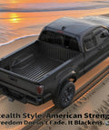 Black pickup truck parked on sandy beach with ocean backdrop and sunset reflecting on the water