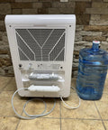 Back view of Fresh Drinking Water From Air Generating Up To 18 Gallons A Day With Multi Stage Filtration unit near bottle