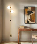 Equinox LED Wall Sconce in gold finish with glass globe shades, mounted beside a desk in a modern home setting