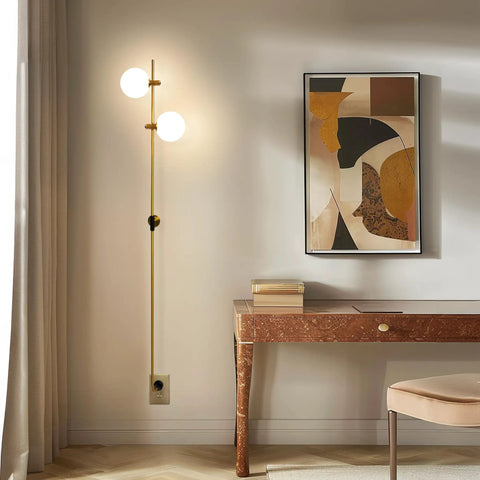 Equinox LED Wall Sconce in gold finish with glass globe shades, mounted beside a desk in a modern home setting