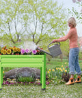 Woman watering plants in elevated raised garden bed with legs heavy duty galvanized steel planter box for vegetables and flowers.