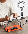Person using Magnetic Helping Hands Soldering Station 2 In 1 With 3X LED Magnifying Lamp 5 Flexible Arms on a workbench.