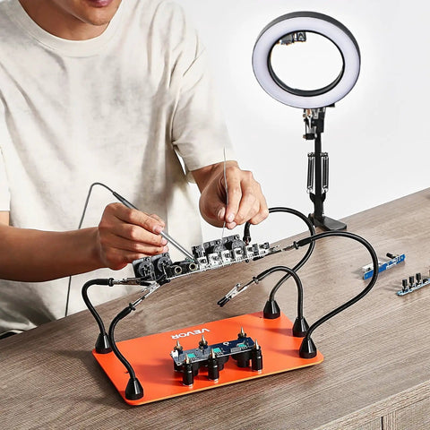 Person using Magnetic Helping Hands Soldering Station 2 In 1 With 3X LED Magnifying Lamp 5 Flexible Arms on a workbench.